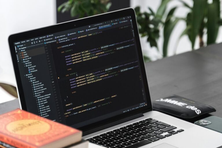 Laptop met code op het scherm voor het automatiseren van bedrijfsprocessen, op een bureau met werkmaterialen.