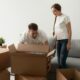 Stel pakt samen dozen in tijdens woning ontruimen, met kartonnen dozen en een bank op de achtergrond.