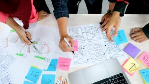 Team werkt samen aan sjablonen voor recruitmentmarketing met wireframes, visuals en post-its op tafel.