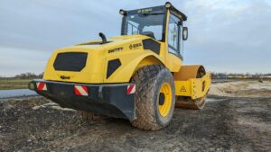 Gele wals staat op bouwterrein met modderige ondergrond